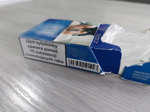 na stole leży paczka po papierosach koloru biało niebieskiego