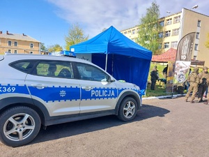 policyjny radiowóz stoi przed stoiskiem promocyjnym Policji