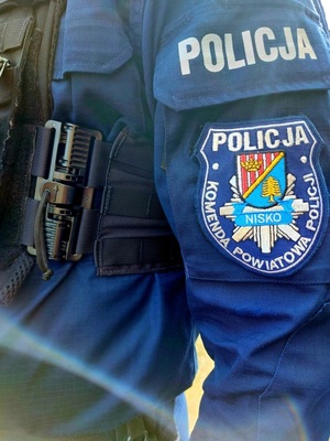 widok przedramienia w granatowej bluzie z naszywką z napisem komenda powiatowa policji w nisku w środku herb miasta
