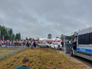 policyjny radiowóz typu bus w tle tłum osób biało czerwone flagi oraz karetka