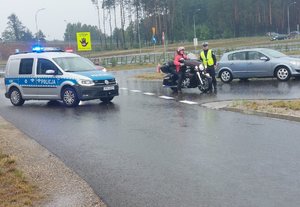 policyjny radiowóz obok policjant z motocyklistą