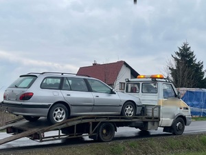 na jezdni stoi laweta na lawecie jest pojazd osobowy typu kombi koloru srebrnego