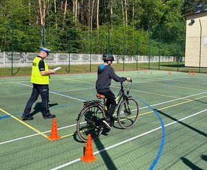 policjant idzie za dzieckiem jadącym na rowerze