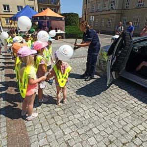 policjantka stoi przed grupą dzieci której pokazuje sprzęt policyjny