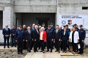 grupa policjantów i osób cywilnych stoi na tle budowy