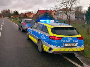 policyjny radiowóz i pojazd osobowy stoja na poboczu jezdni