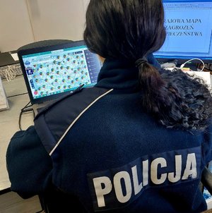 policjantka siedzi przy biurku, na biurku stoi monitor komputera