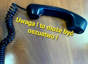 słuchawka telefonu stacjonarnego leży na biurku. przy niej napis uwaga! to może być oszustwo !