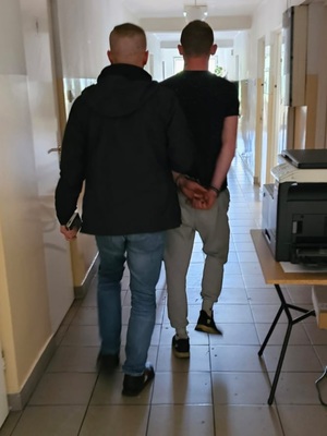 mężczyzna prowadzi osobę w kajdankach