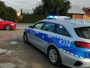 policyjny radiowóz stoi na poboczu przed nim osobowe czerwone auto