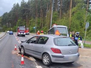 uszkodzony samochód osobowy na jezdni w tle policjanci i wóz strażacki