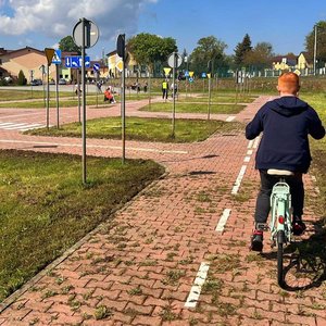 chłopiec jedzie na rowerze przez miasteczko ruchu drogowego w tle policjant ruchu drogowego