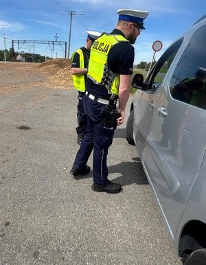 policjanci stoją przy samochodzie typu bus