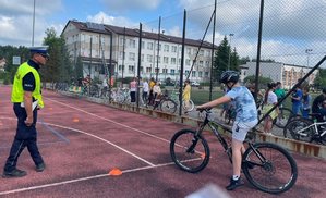 policjant ruchu drogowego obok niego jedzie dziecko na rowerze