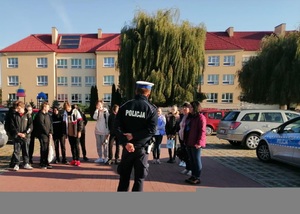 policjant stoi przed grupą młodzieży