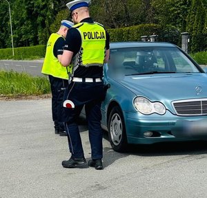 policjanci ruchu drogowego stoją przy samochodzie osobowym