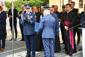 policjanci oraz osoby cywilne stoją pod zadaszeniem