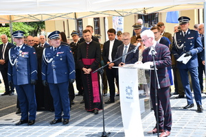 policjanci i osoby cywilne stoją pod zadaszeniem