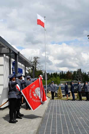 policjanci stoją w rzędzie ze sztandarem w tle flaga państwowa