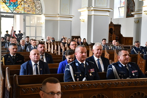 policjanci i osoby cywilne siedzą w ławkach w kościele