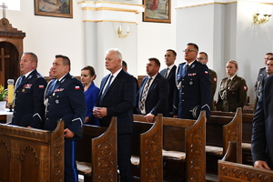 policjanci i osoby cywilne stoją w kościelnych ławkach