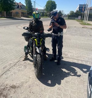 policjant stoi obok motocyklisty