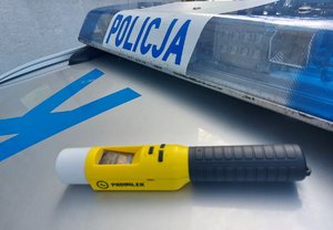 napis policja na belce świetlno dźwiękowej na dachu radiowozu obok leży urządzenie do badania stanu trzeźwości z napisem promiler