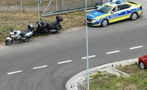 dwa motocykle stoją przed radiowozem osobowym w tle las obok droga