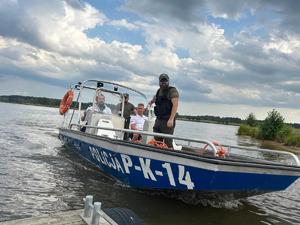 na łodzi na wodzie są policjanci i funkcjonariusze państwowej straży rybackiej