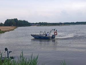 policjant pływa łodzią po zbiorniku wodnym