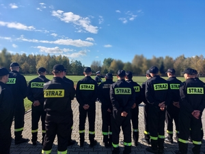 policjant stoi przed grupą strażaków