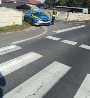 policjant stoi przy przejściu dla pieszych prowadzi pomiar prędkości pojazdów