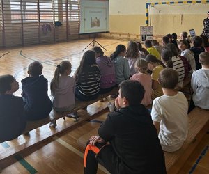 uczniowie siedzą na sali oglądają prezentację