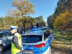 policjanci stoją przy drodze po której poruszają się pojazdy