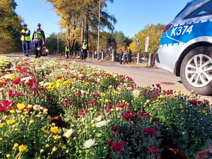 policjanci kierują ruchem na jezdni po której chodzą piesi i jadą pojazdy