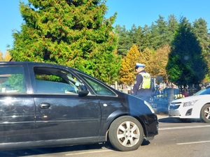 policjanci kierują ruchem na jezdni po której chodzą piesi i jadą pojazdy