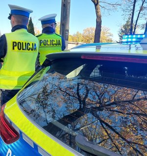 policjanci stoją przy radiowozie