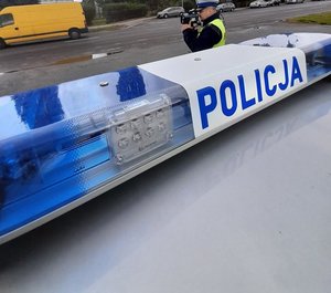 policjant prowadzi pomiar prędkości pojazdów przy drodze