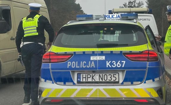 policyjny radiowóz obok którego stoi dwoje policjantów