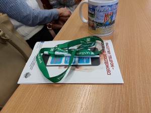 fałszywy telefon zagrożone oszczędności - opis na ulotce informacyjnej obok leży długopis smycz oraz kubek