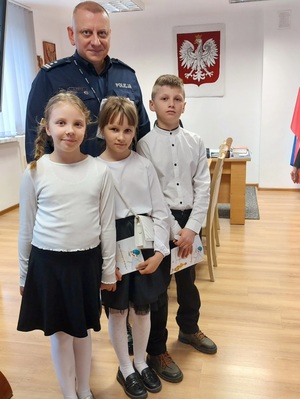 dzieci stoją przy policjancie w gabinecie