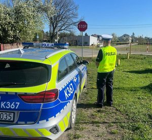 policjant przy drodze obok policyjny radiowóz
