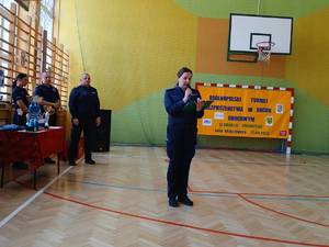 policjantka mówi do mikrofonu na hali sportowej w tle policjant