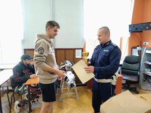 policjant wręcza uczniowi dyplom i puchar
