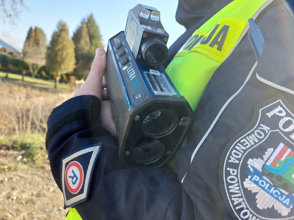 policjant trzyma w ręku urządzenie do pomiaru prędkości