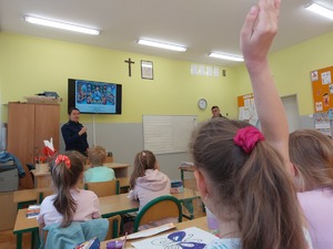 policjanci podczas prelekcji w szkolnej klasie w ławkach siedzą dzieci