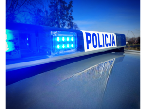 policyjna belka na dachu radiowozu z napisem policja i włączonymi światłami błyskowymi koloru niebieskiego