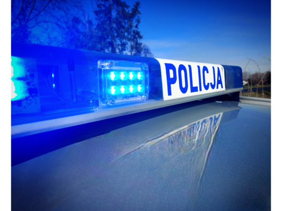 policyjna belka na dachu radiowozu z napisem policja i włączonymi światłami błyskowymi koloru niebieskiego