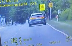 screen z policyjnego videorejestratora z widokiem pojazdu osobowego jadącego wzdłuż drogi z wyświetloną wartością 102 km/h