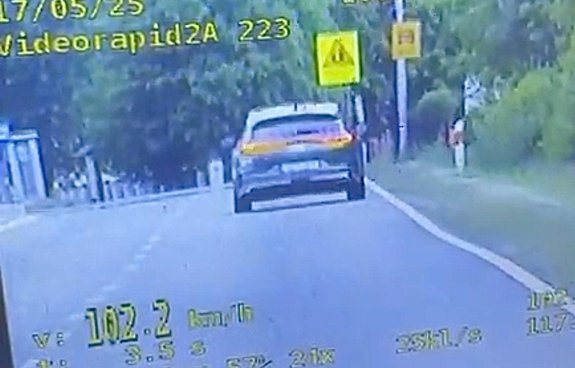 screen z policyjnego videorejestratora z widokiem pojazdu osobowego jadącego wzdłuż drogi z wyświetloną wartością 102 km/h